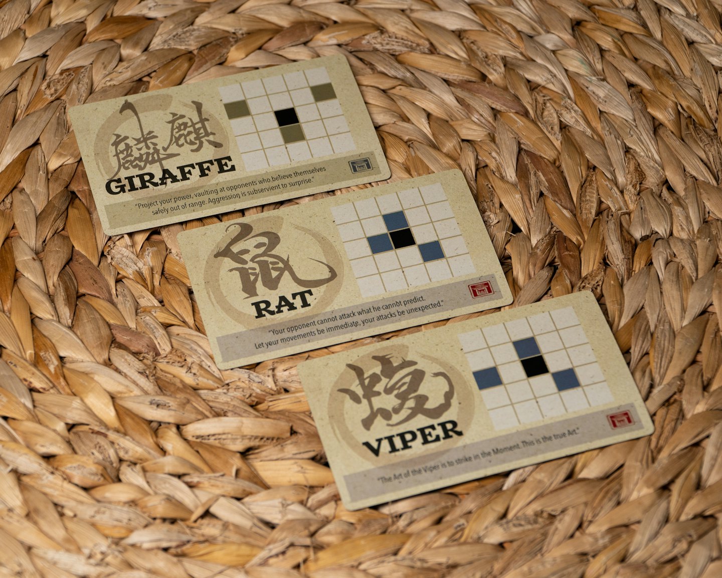 Three Japanese game cards with animal names on a woven mat.