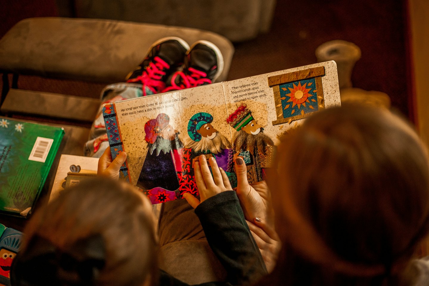 Adult reading a colorful children's book to a child.