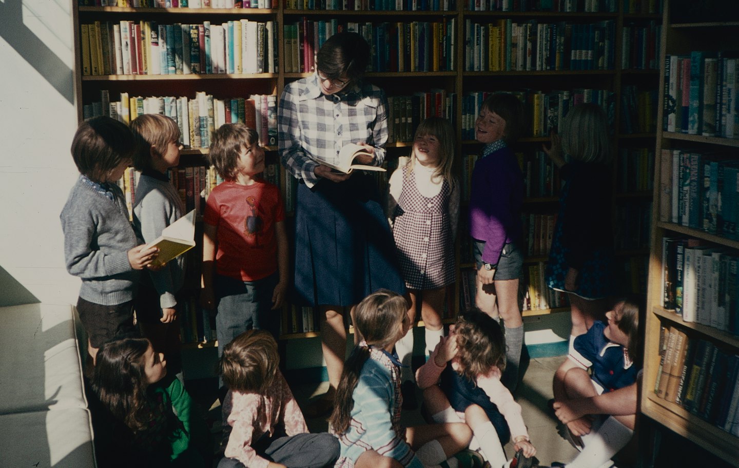 Teacher reads to attentive children in a bright library.