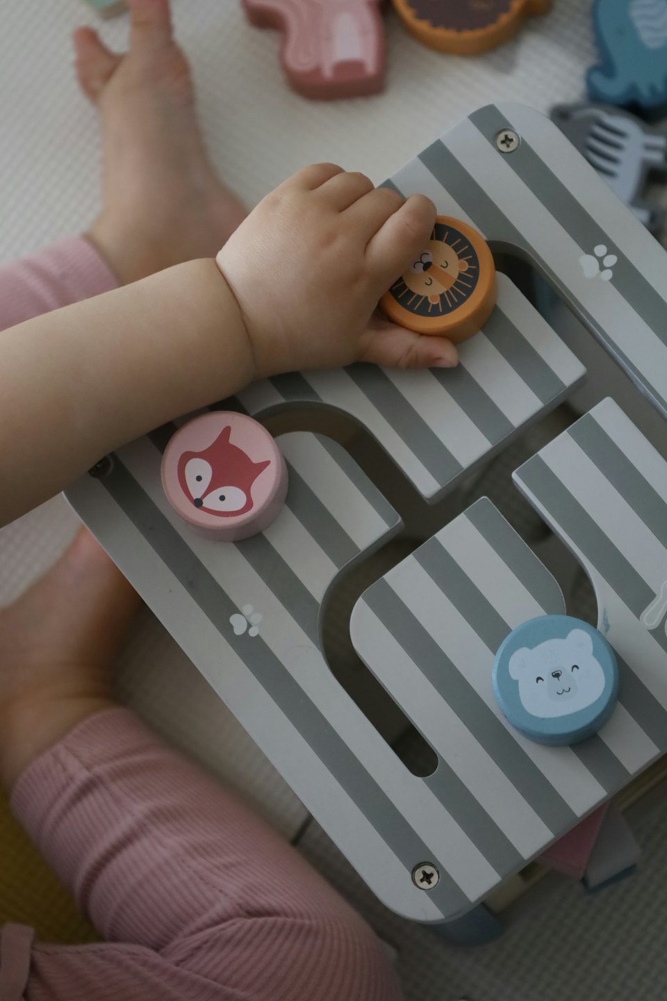 Child's hands playing with a wooden animal maze toy.