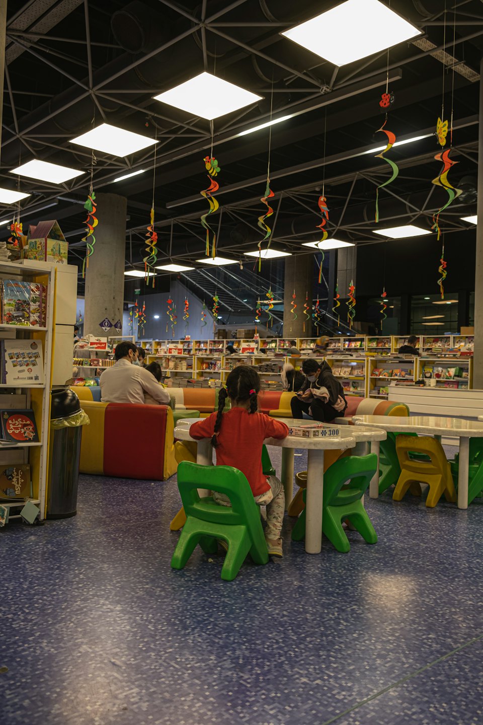 Children playing with games inside a library with colorful decorations.